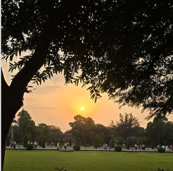 Un coucher de soleil sur un parc où l’on voit des gens se promener et des arbres. 2