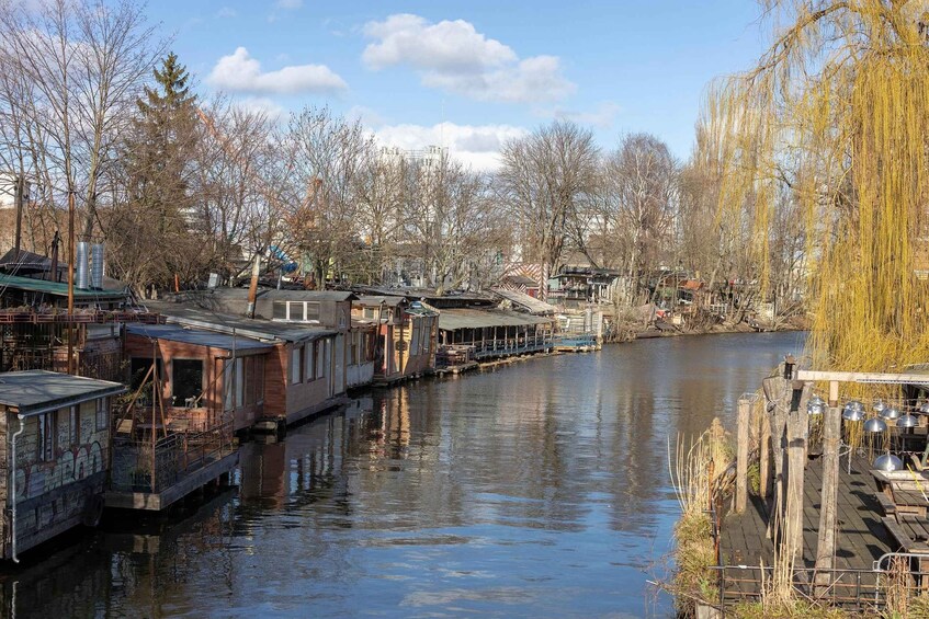 A river with floating houses, a wooden dock, and leafless trees. 1