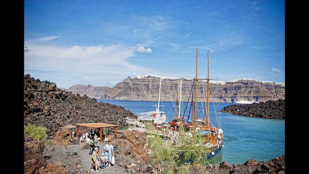A rocky coastal area with a sailboat docked near a sheltered cove, surrounded by rugged cliffs and clear blue water. 5