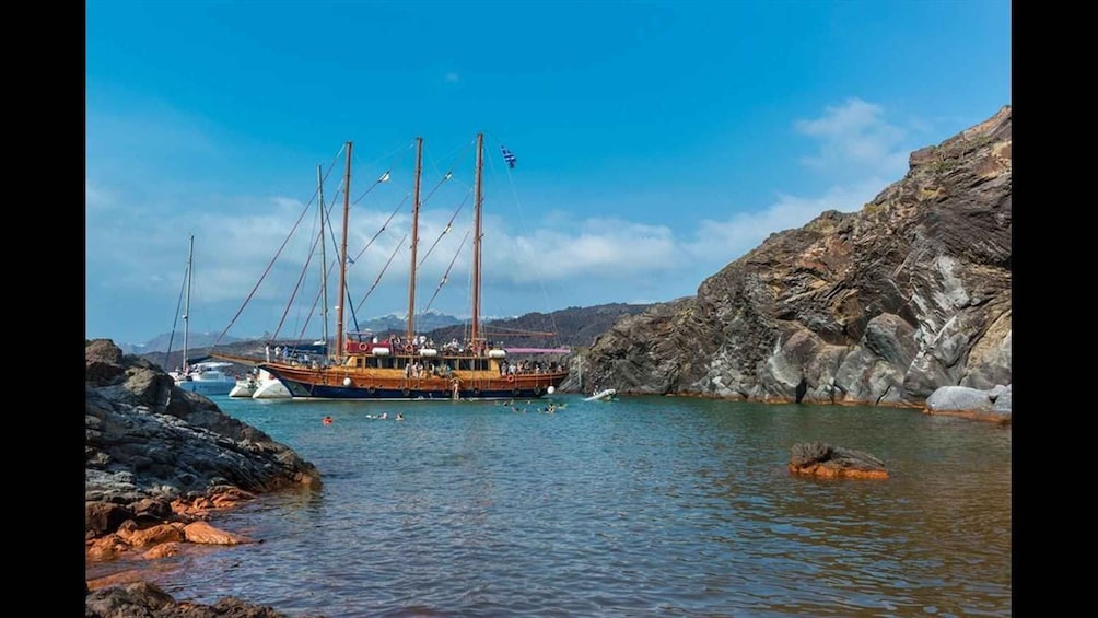 A large sailing ship docked at a rocky harbor with clear skies. 3
