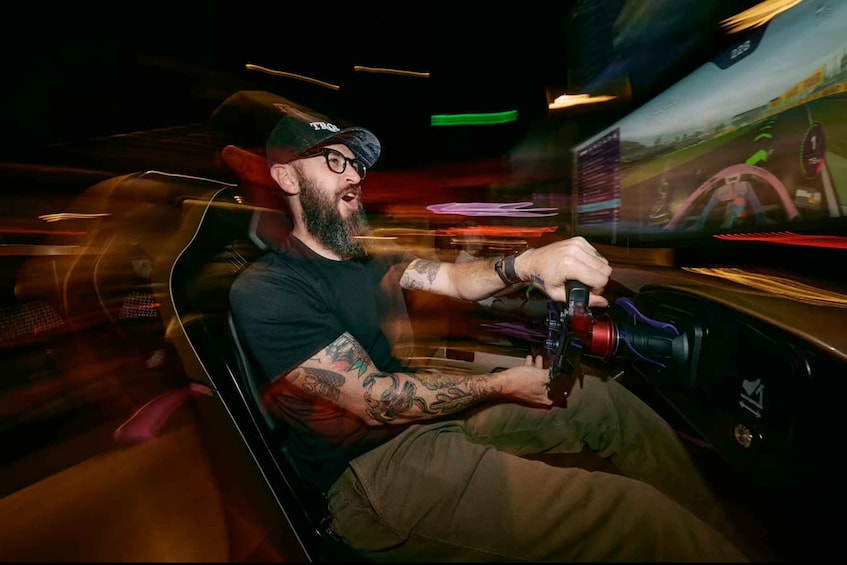 A person driving a racing simulator with a steering wheel and pedals. 1