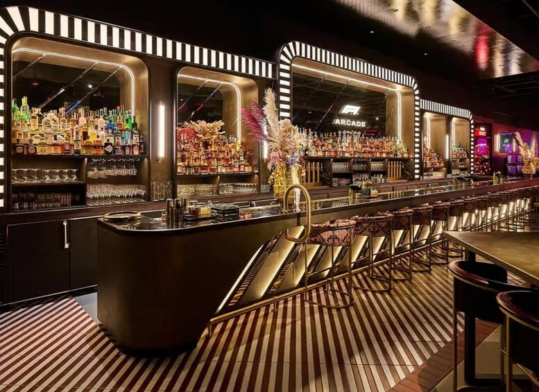 A bar with striped flooring, a central bar counter, and shelves of liquor bottles. 2