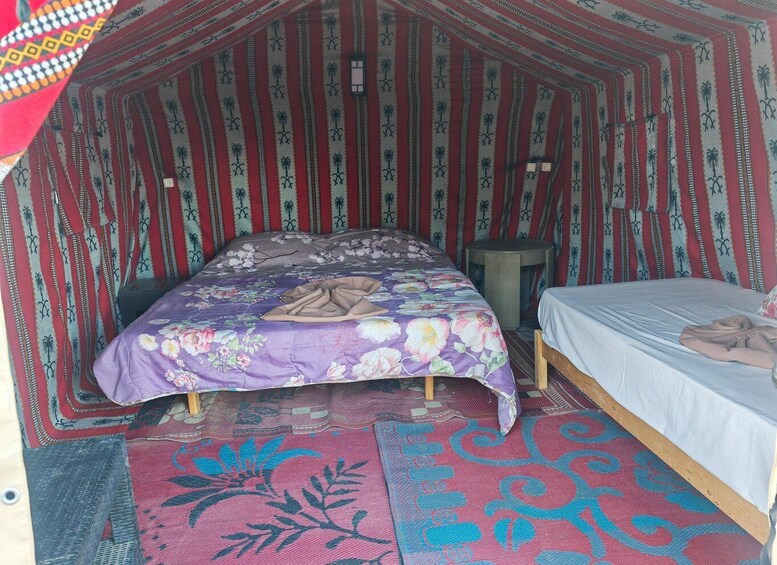 A cozy, tent-like room with a bed, a small table, and patterned rugs. 4