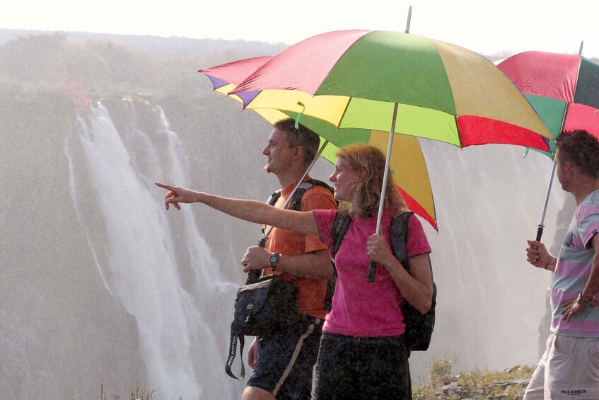 A waterfall with people standing under colorful umbrellas. 5