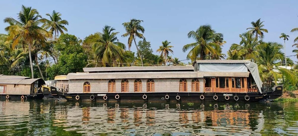 A traditional houseboat with multiple levels, surrounded by palm trees and water. 1