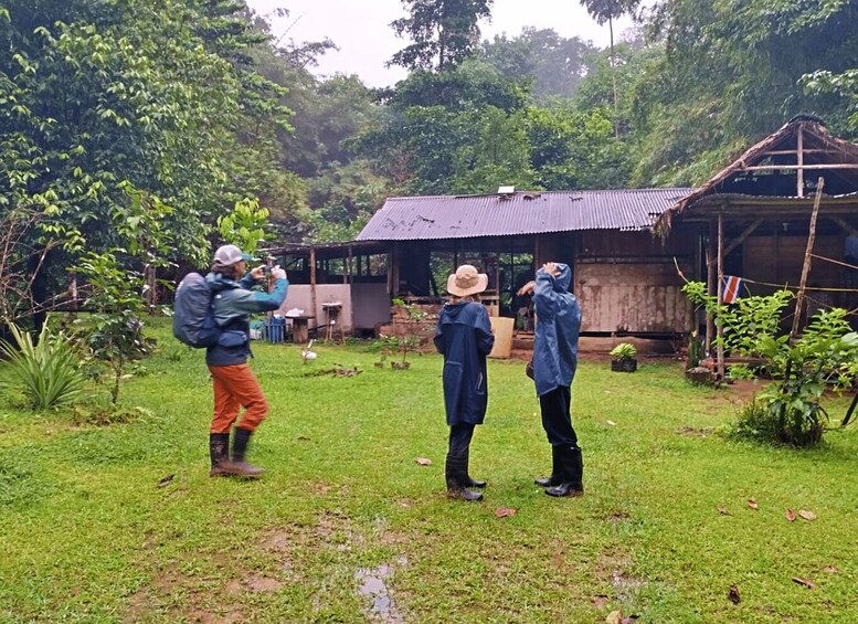 Three people in a grassy area with a rustic building in the background. 2