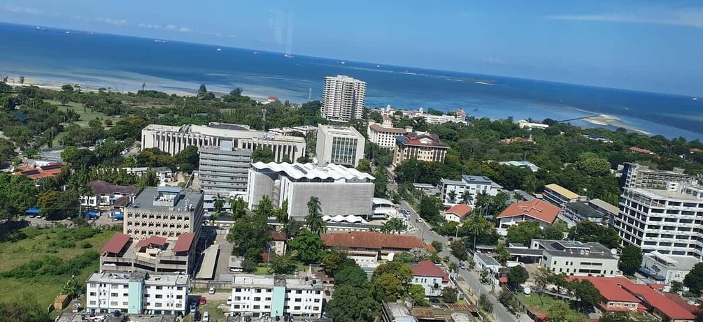 A coastal cityscape with a mix of modern and traditional architecture, a prominent white building, and a view of the ocean. 4