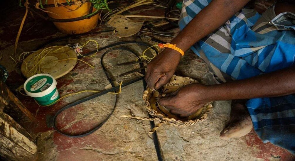 A person weaving with a basket on the ground. 2