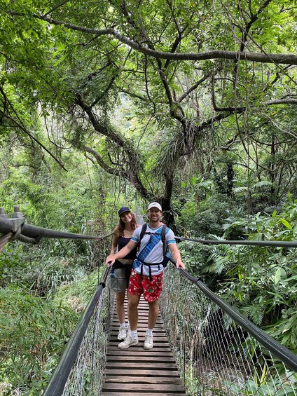A couple on a suspension bridge surrounded by dense forest. 2