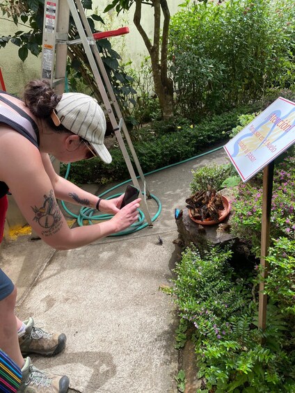 A person watering plants with a hose in a garden with a sign warning about snakes. 4