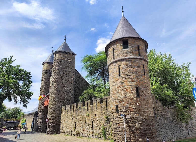 A historic stone castle with two prominent towers and a surrounding wall. 1
