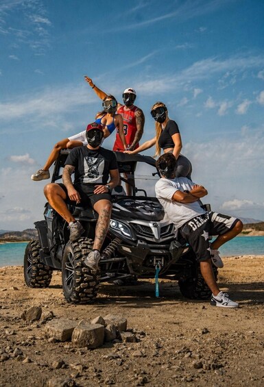 A group of people on an ATV on a rocky beach with clear skies. 2
