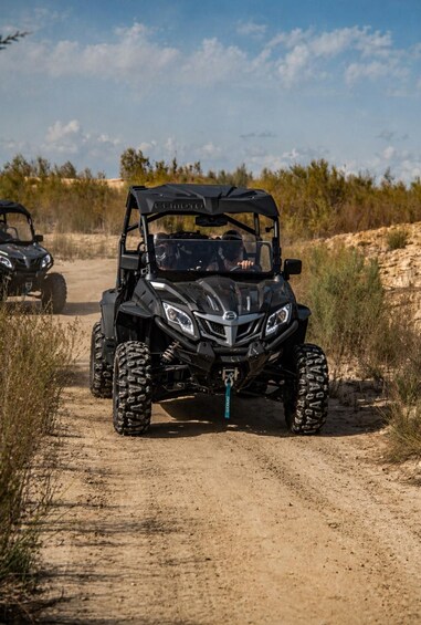 A black ATV on a dirt path with vegetation on either side. 3