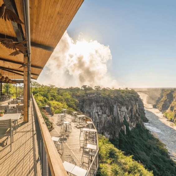 A wooden deck overlooking a river canyon with a bridge in the distance. 3