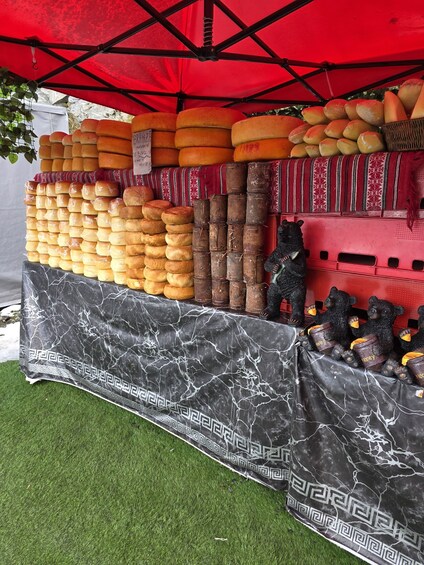 A cheese stand with various cheeses and honey jars under a red canopy. 4