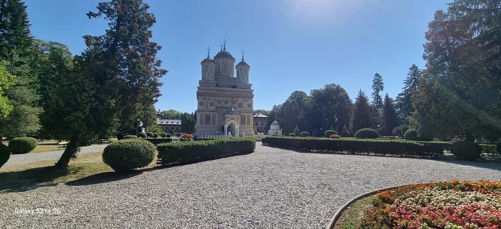 A historic church with a bell tower, surrounded by well-manicured gardens and trees. 5