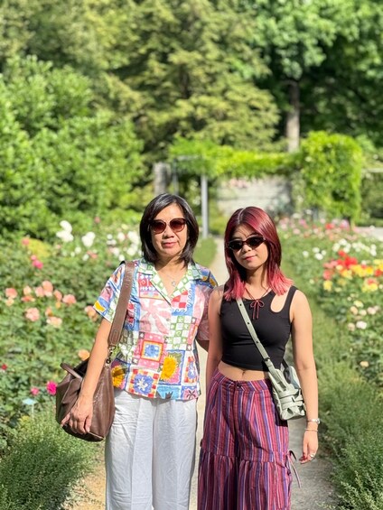 Two people walking on a garden path surrounded by flowers and greenery. 2