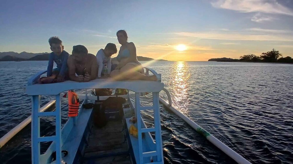 A group of people on a boat at sunset with mountains in the background. 1