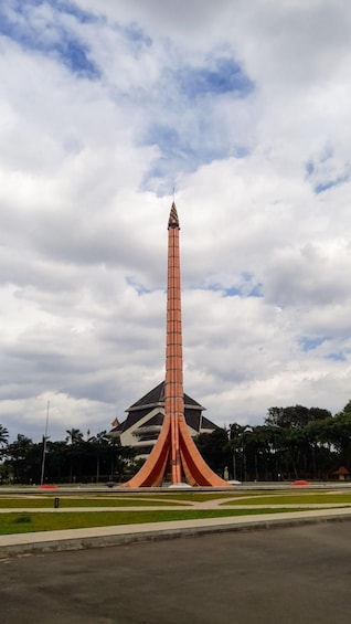 A tall, slender tower with a pointed top, surrounded by a landscaped area with grass and trees. 5