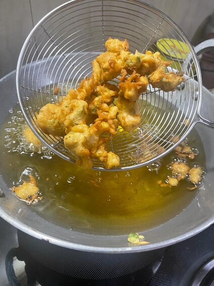 A frying basket filled with battered food items being lifted out of hot oil. 4