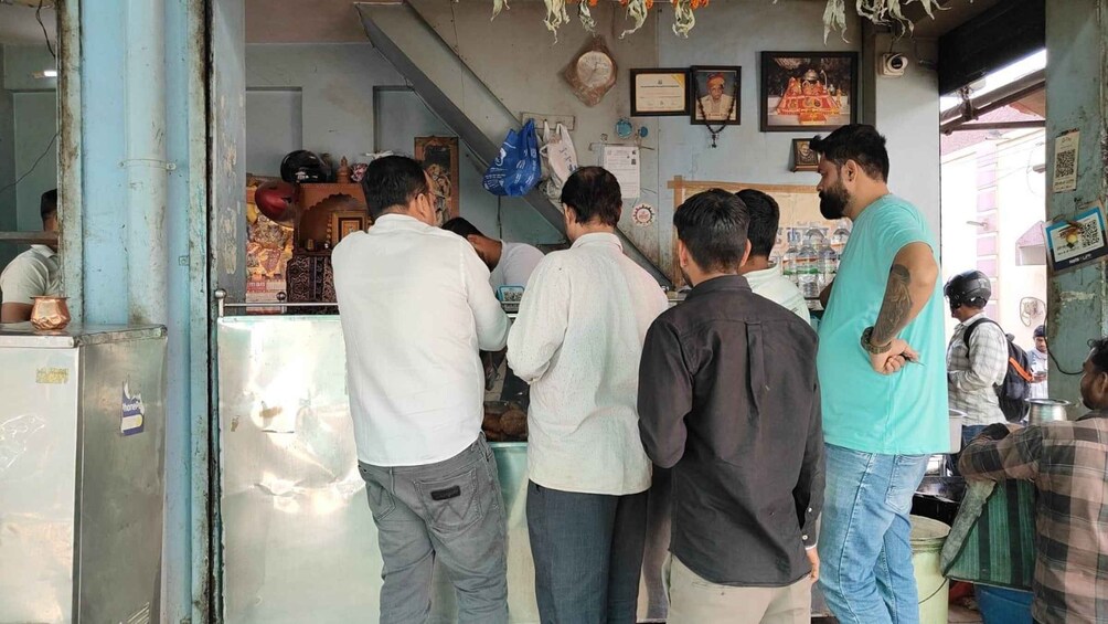 A group of people standing at a counter in a shop with various items and decorations on the walls. 5