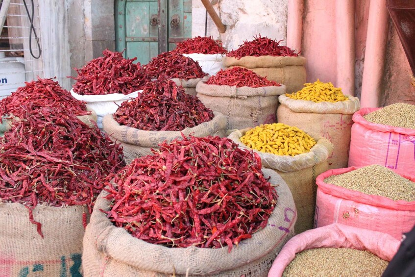 Sacks of dried red chilies and yellow grains, likely at a market. 1