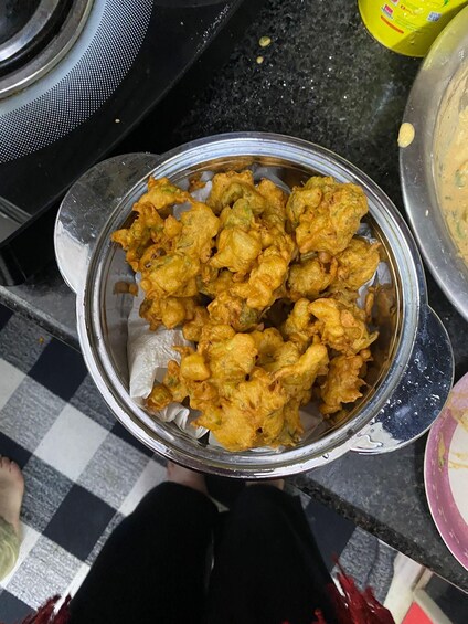 A bowl of fried food with a checkered floor in the background. 2