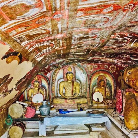 A temple interior with three golden Buddha statues, a ceiling with intricate patterns, and various ritual items. 1