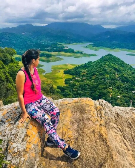 A person sitting on a rock overlooking a mountainous landscape with a lake. 4