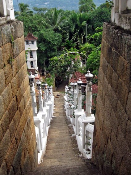 A stone staircase flanked by white railings leading to a traditional building with a tiled roof. 3