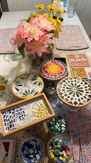 A table with mosaic tiles, a vase of flowers, and a glass of water. 3