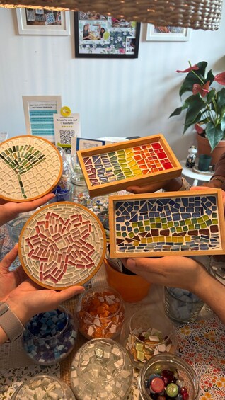 A person holding mosaic tile boxes with various colored tiles. 5