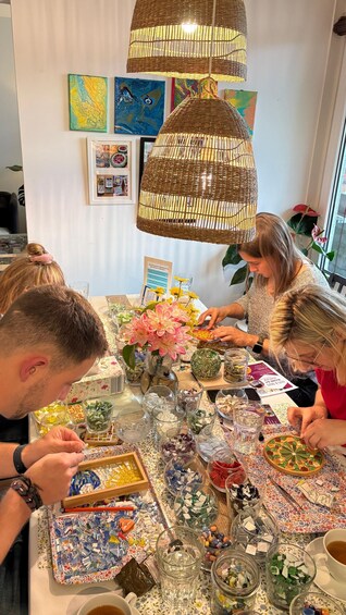 A group of people at a table with various colorful glass objects and a decorative lamp. 2