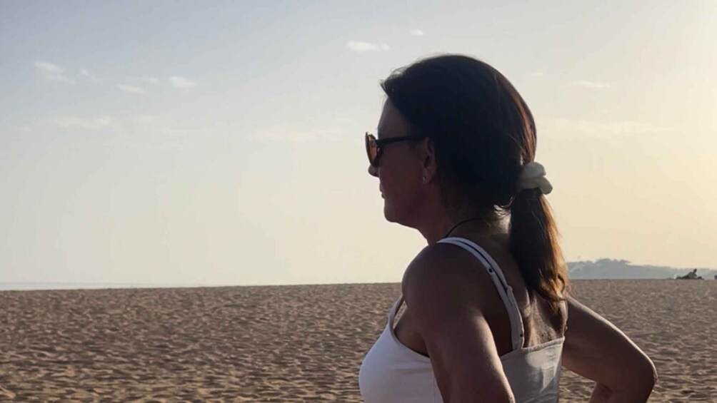 A person standing on a sandy beach with a clear sky. 2