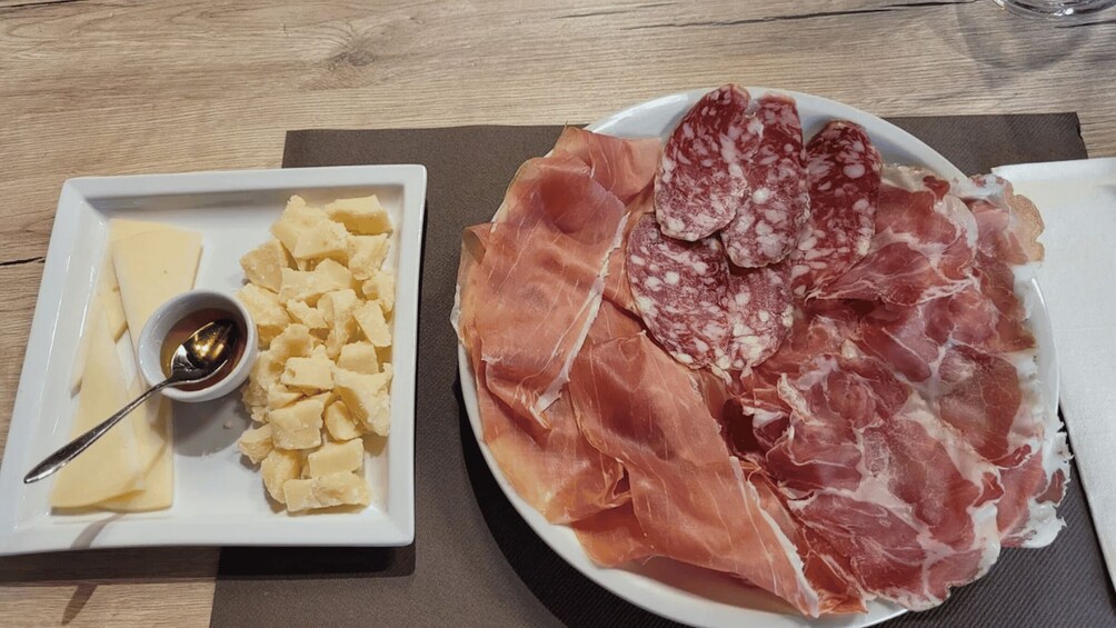 A plate of cured meats and cheese with a spoon. 3
