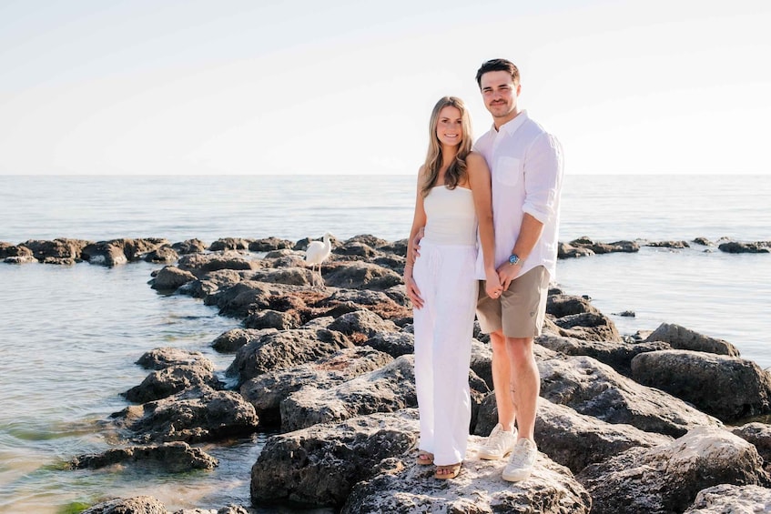 A couple standing on rocky terrain by the sea. 5