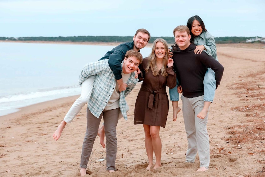 A group of people on a sandy beach with a body of water in the background. 3