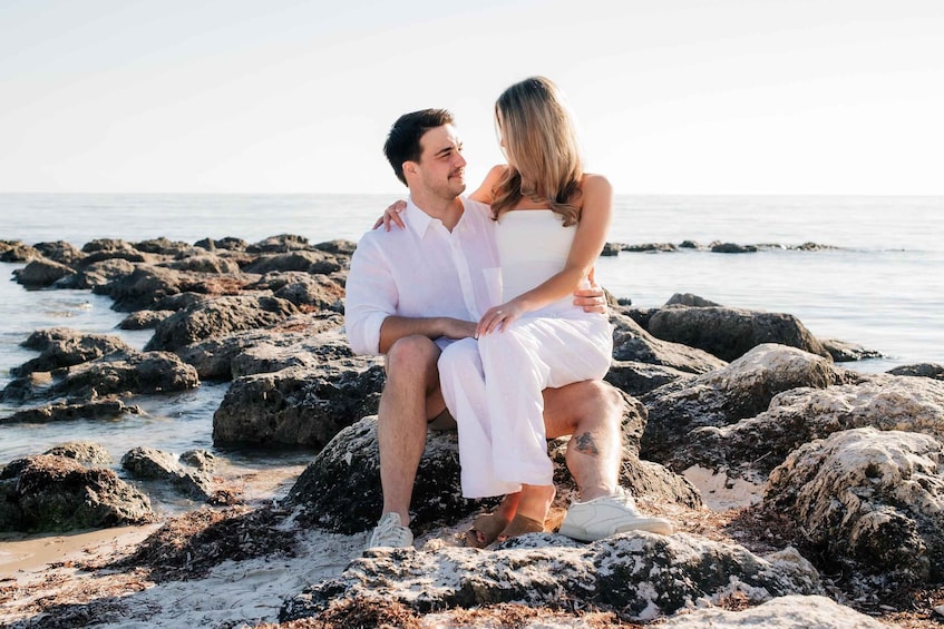A couple sitting on rocks by the sea. 1
