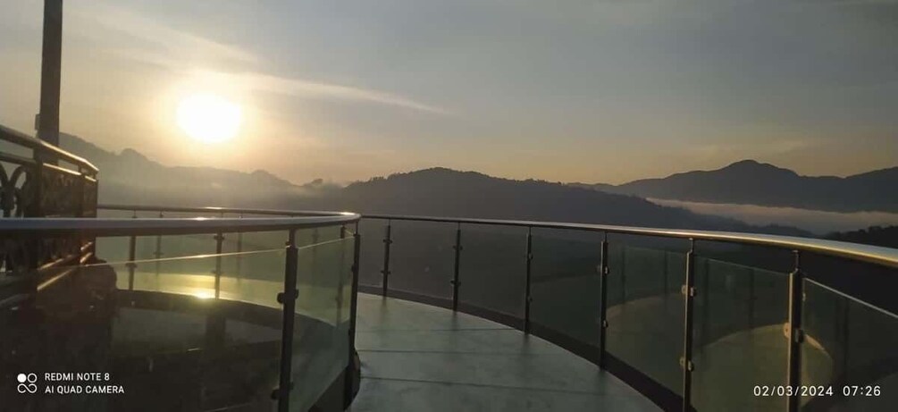 A sunset over mountains with a glass railing. 5