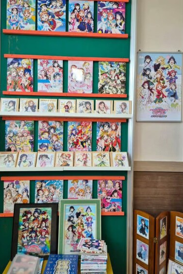 A wall with multiple anime posters and framed pictures. 2