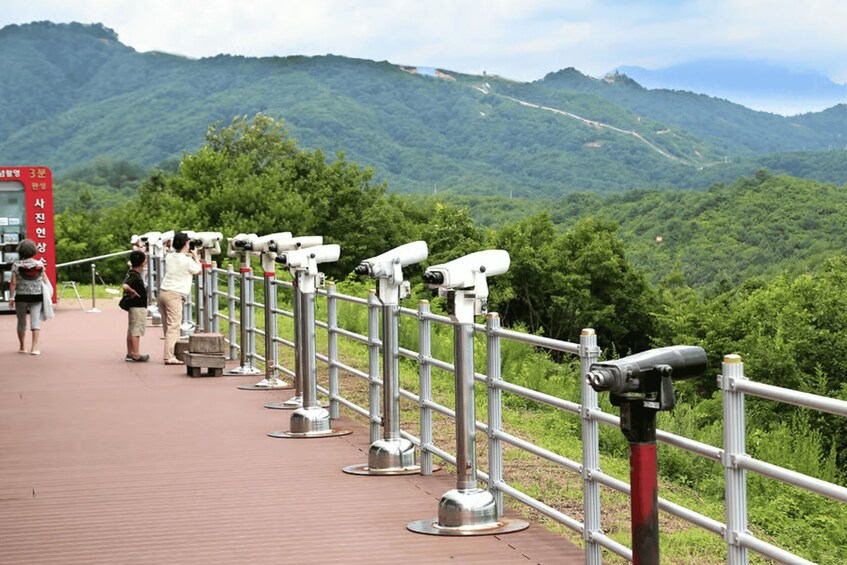 A viewing platform with telescopes overlooking a mountainous landscape. 3