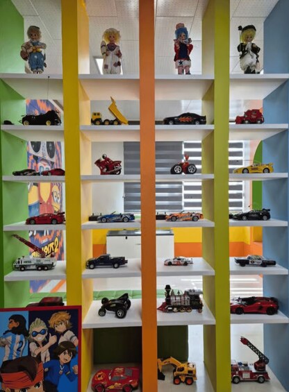A collection of toy cars and trucks on shelves, with colorful walls and a central column. 4