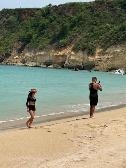 A beach with clear turquoise water, a sandy shore, and rocky cliffs in the background. 5