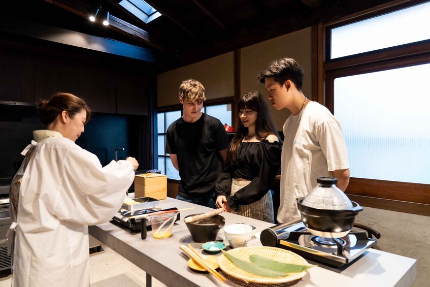A group of people in a kitchen with cooking utensils and a stove. 1