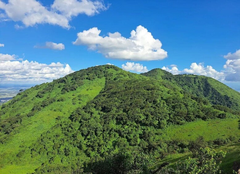 A lush green mountain range under a clear blue sky. 1