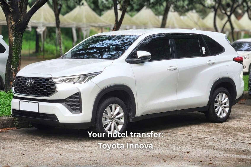 A white Toyota Innova parked on a concrete surface with trees and other vehicles in the background. 5