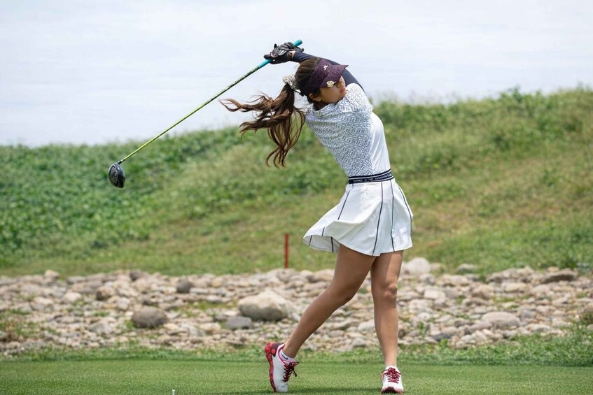 A golfer in mid-swing on a golf course. 2