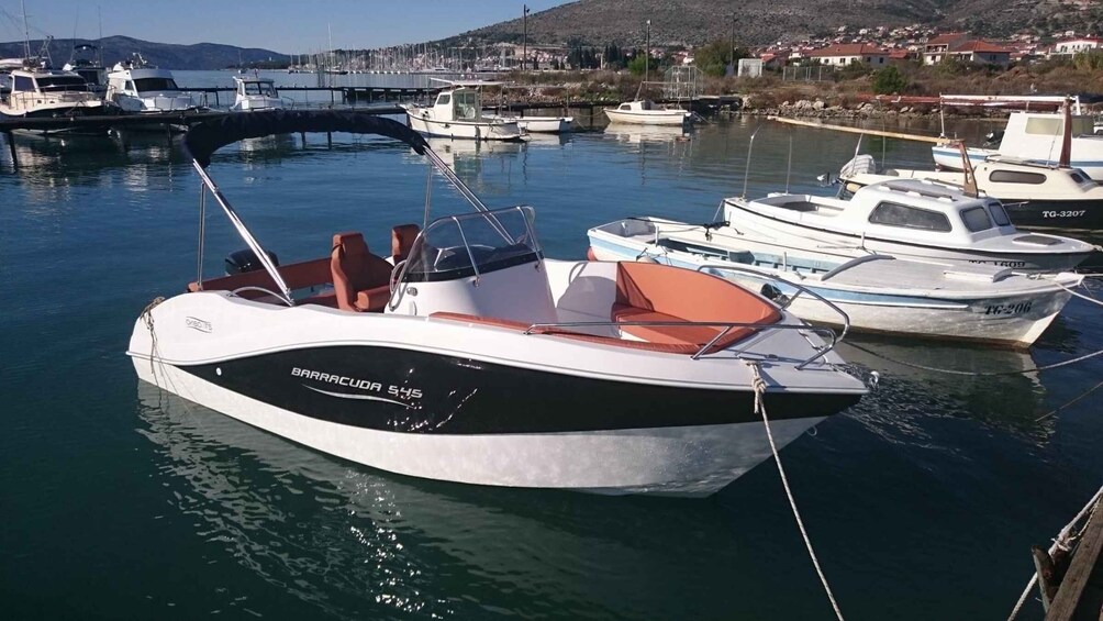 A marina with several boats docked, including a Barracuda 545 speedboat prominently in the foreground. 4