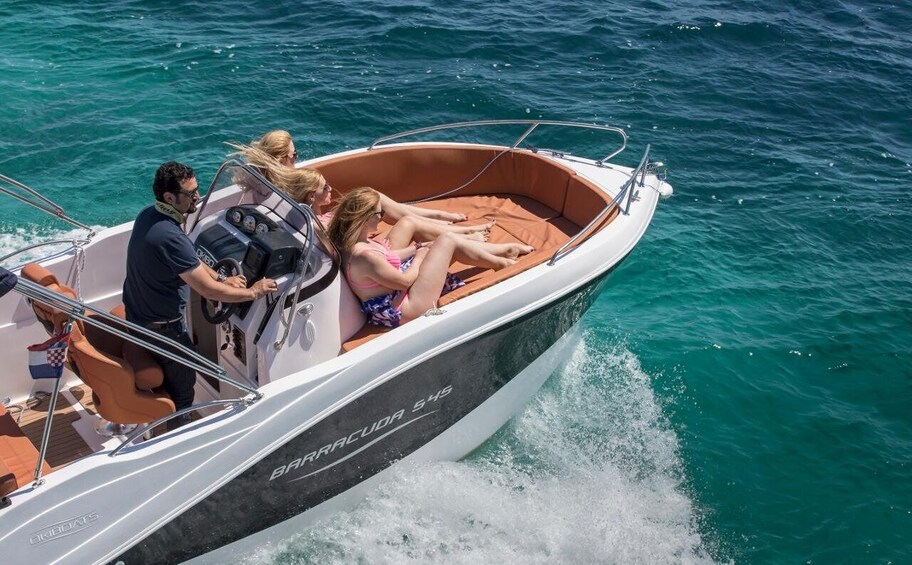 A motorboat with passengers, a man steering, and a woman reclining. 1