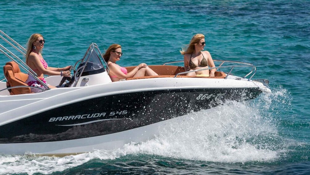 Three people on a motorboat with 'BARRACUDA 545' written on the side. 2